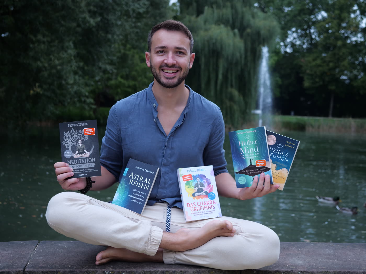 Andreas Schwarz im Lotussitz mit seinen Büchern